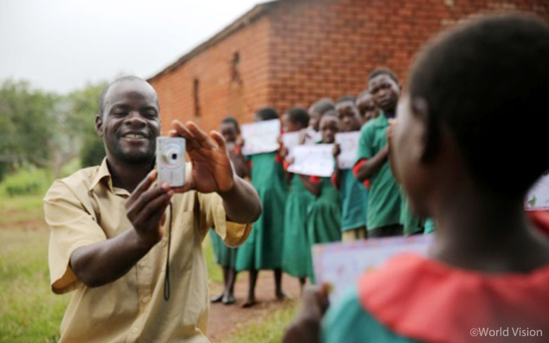 스마일~ 치즈~ 아동의 눈높이에 맞추어 사진을 찍는 자원봉사자.