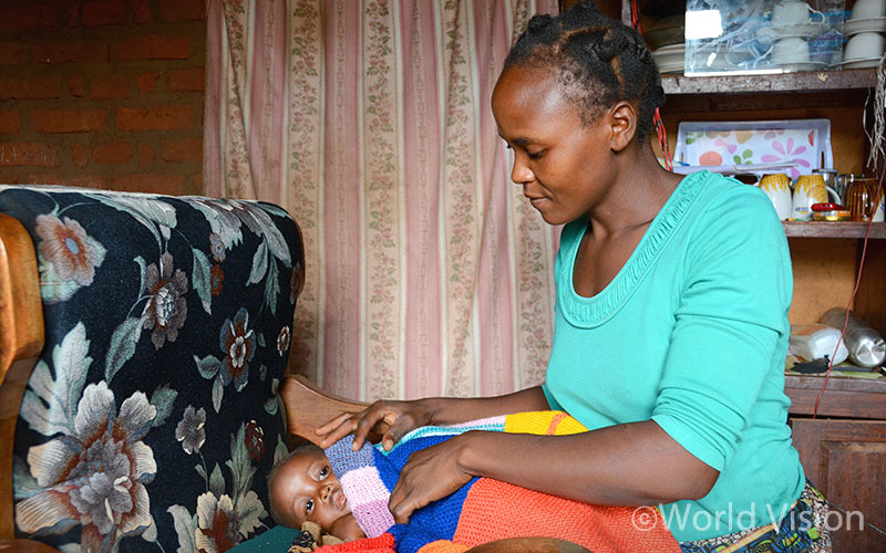 엠마누엘을 침대에 눕히며 담요를 덮어주는 엄마 그레이스
