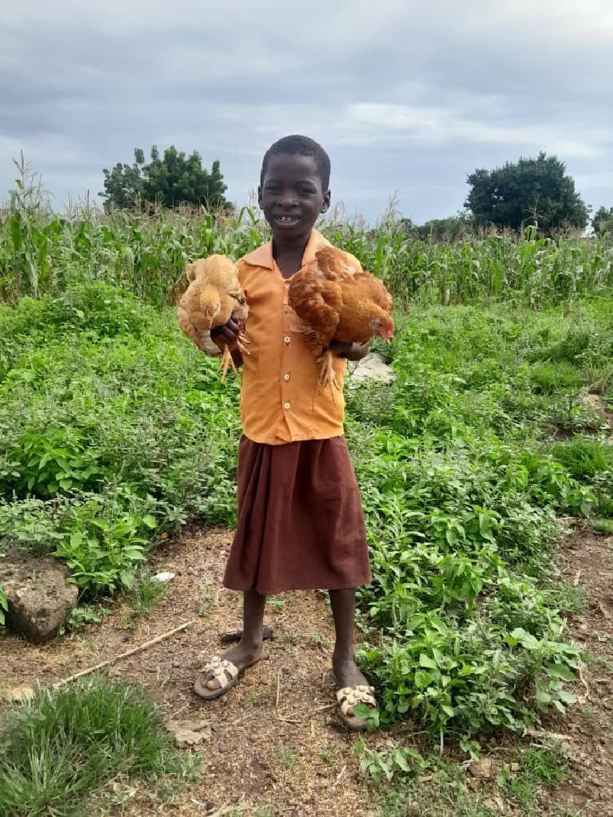 닭을 들고 미소짓느 가나 아동