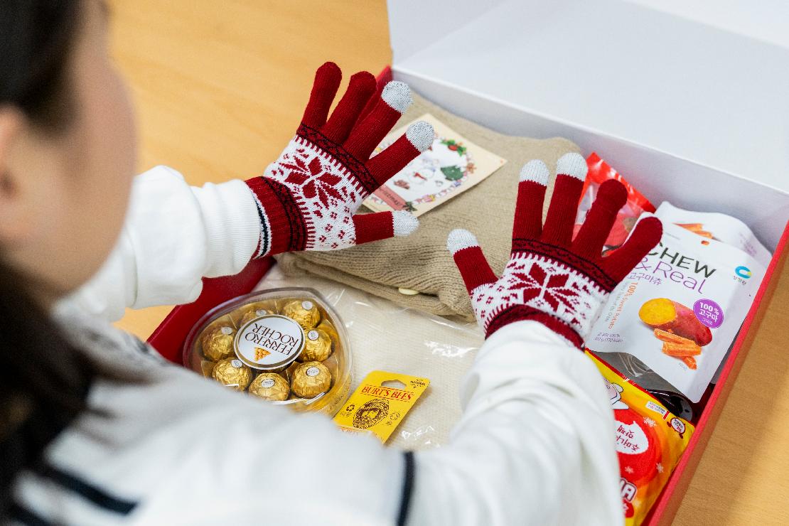 한 아이가 성탄키트를 열고 장갑을 착용해보는 모습